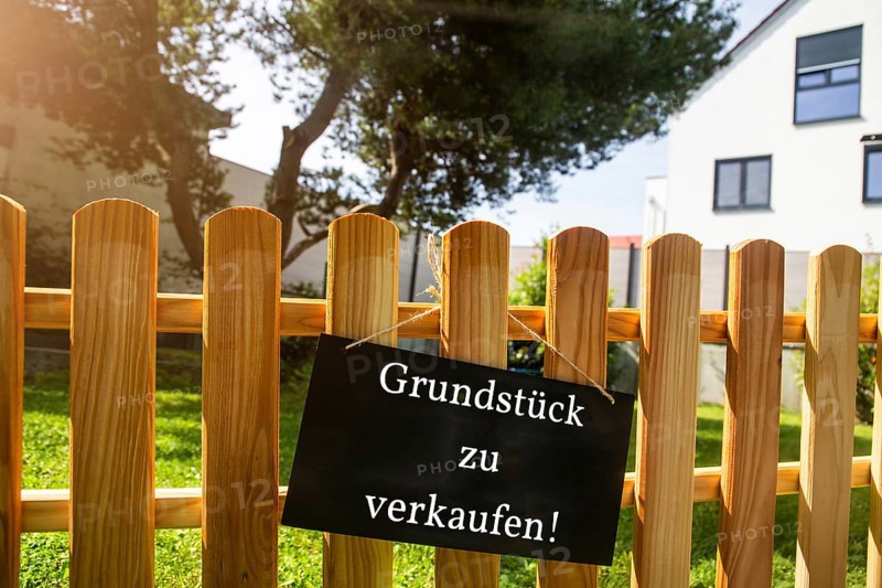 Sign with the inscription GRUNDSTÜCK ZU VERKAUFEN on a wooden fence (symbolic image)