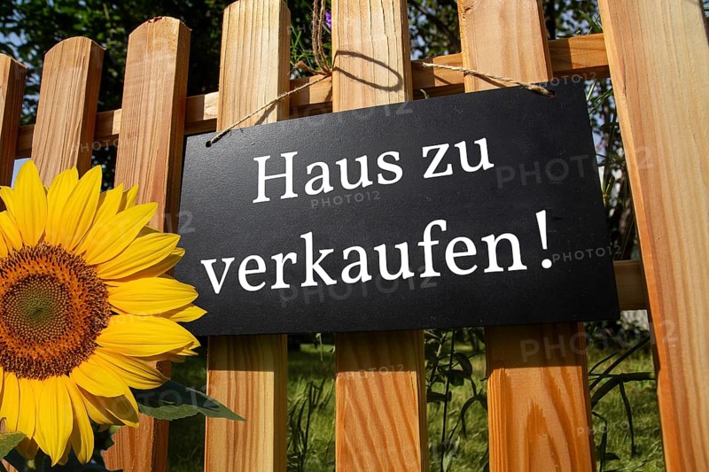 Sign with the inscription HAUS ZU VERKAUFEN on a wooden fence (symbolic image)