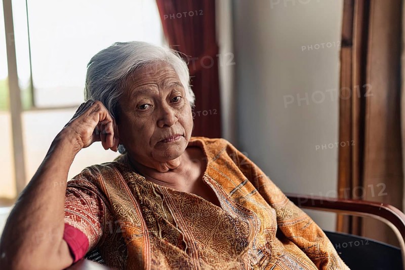 Dementia, Elderly woman in traditional dress sits thoughtfully in a room in daylight, ai generated, KI generated
