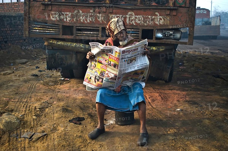 Muslim man reading the newspaper in the street (Dhanbad, Jharkhand, India) . The newspaper is written in hindi