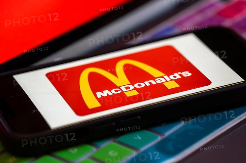 In this photo illustration, McDonald's logo is displayed on a smartphone with a laptop display background. McDonald's sales fall globally for first time in over three years, reports