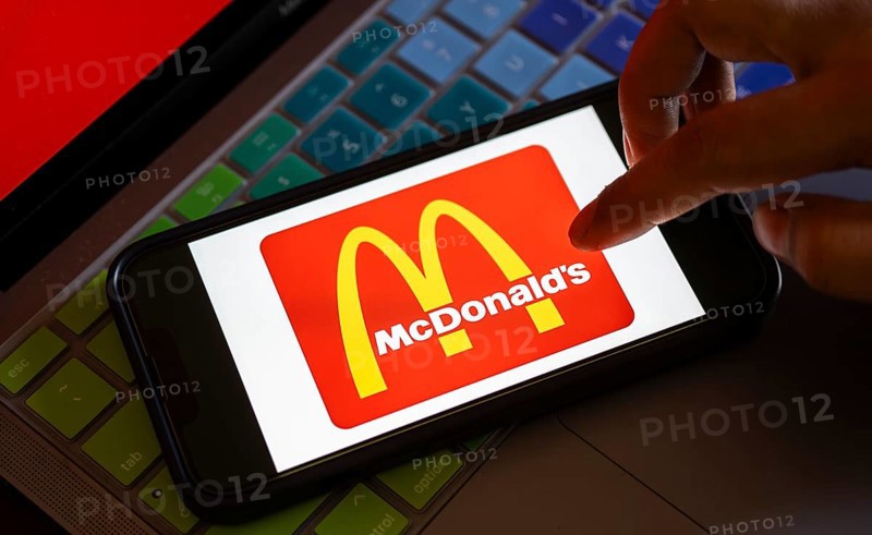 In this photo illustration, McDonald's logo is displayed on a smartphone with a laptop display background. McDonald's sales fall globally for first time in over three years, reports