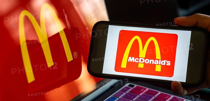 In this photo illustration, McDonald's logo is displayed on a smartphone with a laptop display background. McDonald's sales fall globally for first time in over three years, reports