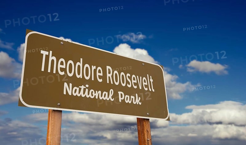Theodore roosevelt national park (north dakota) road sign against blue sky and clouds