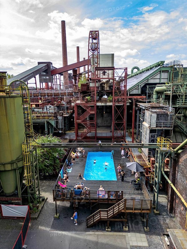 The works swimming pool at the Zollverein coking plant, always in operation during the North Rhine-Westphalia summer holidays, former art object, now bathing fun against the backdrop of what was once Europe's largest central coking plant, closed in 1993, part of the UNESC World Heritage Zollverein Coal Mine Industrial Complex, Essen, North Rhine-Westphalia, Germany, Europe