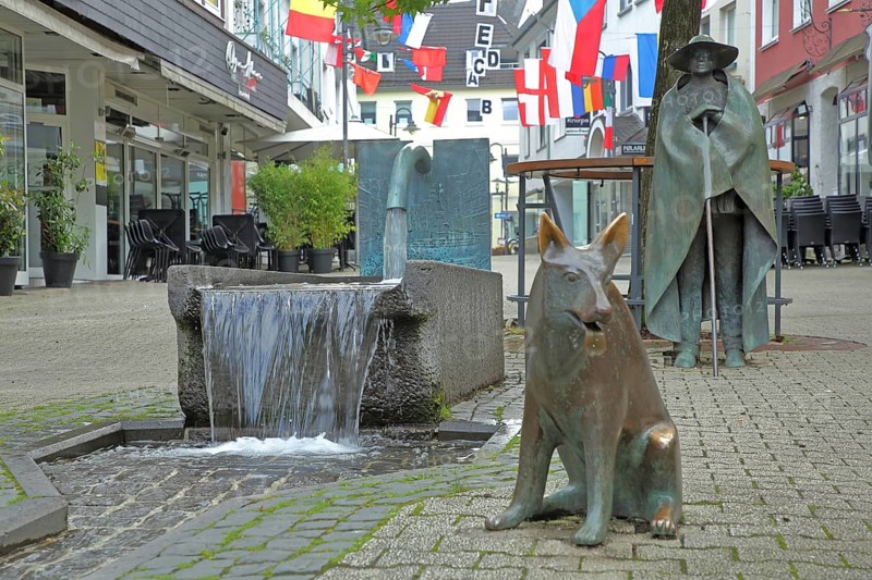 Sculptures Shepherd fountain Cow herd with shepherd by Wolfgang Kreutter 1986, bronze, shepherd with staff, fountain, water jet, dog figure, shepherd dog, shepherd dog, sitting, pedestrian zone, Alte Poststrasse, Siegen, Siegerland, North Rhine-Westphalia, Germany, Europe