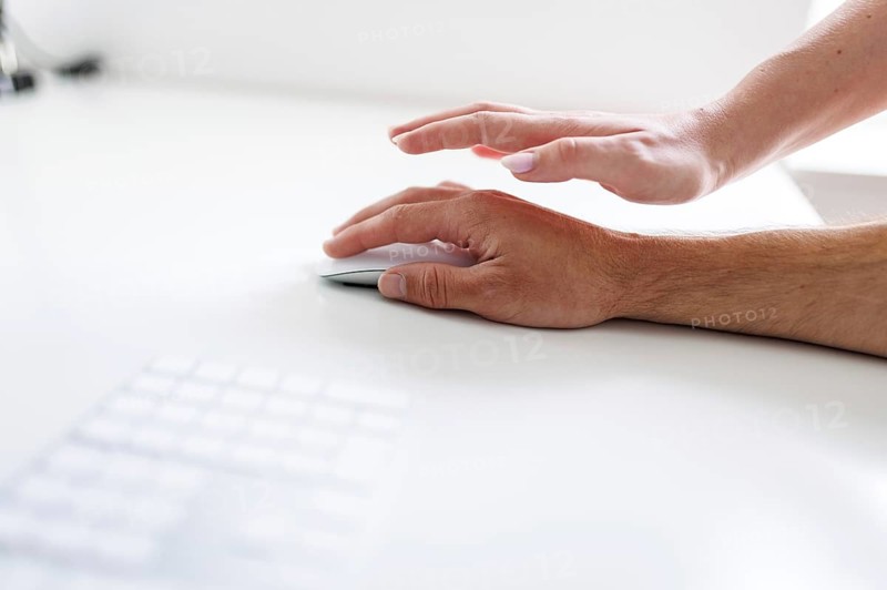 Topic: Sexual violence in the workplace. A woman's hand reaches for a man's hand at a desk in Berlin, 25/07/2024