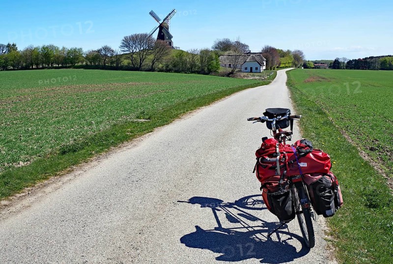 A loaded bicycle on a rural road, windmill and houses in the background, cycle tourism, Manor Route, Skovsgaard Langeland, Denmark, Europe