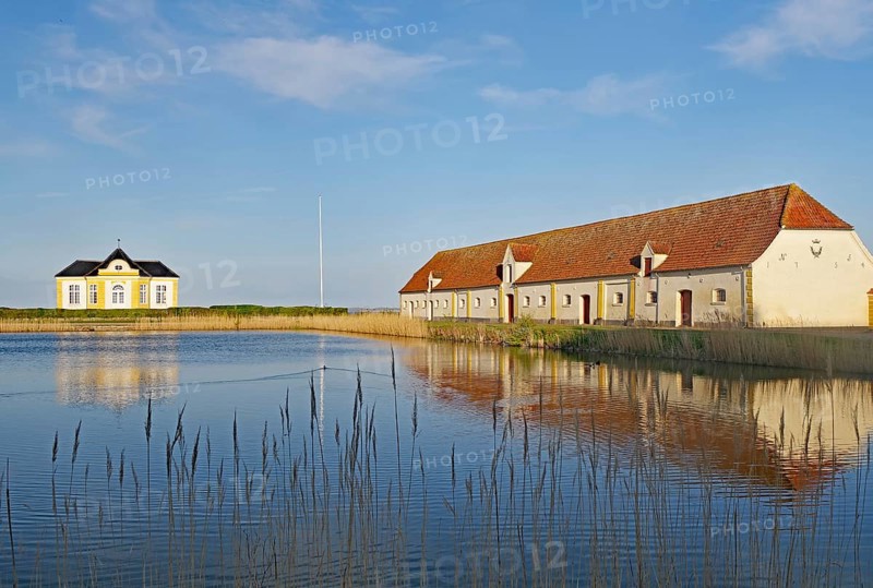Building and house by the lake with reflection in the calm water under a blue sky, Valdemars Slot, Tasinge, Manor Route, Denmark, Europe