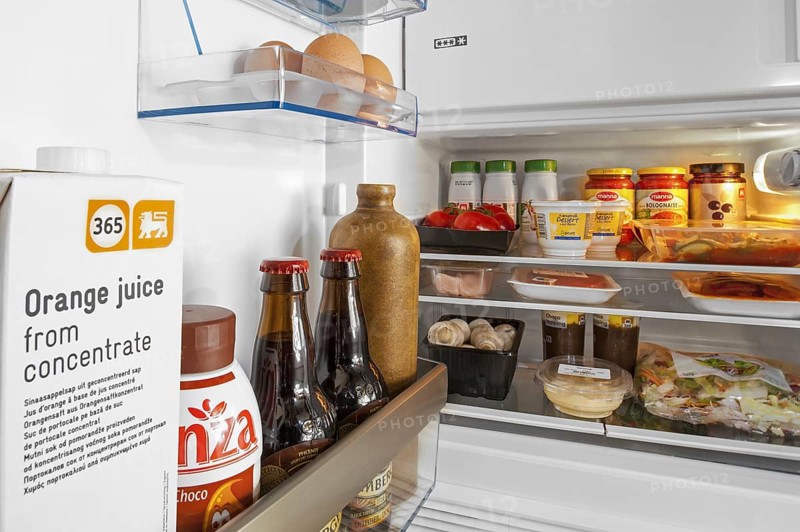 Cooled food and beverages in open fridge, refrigerator in kitchen