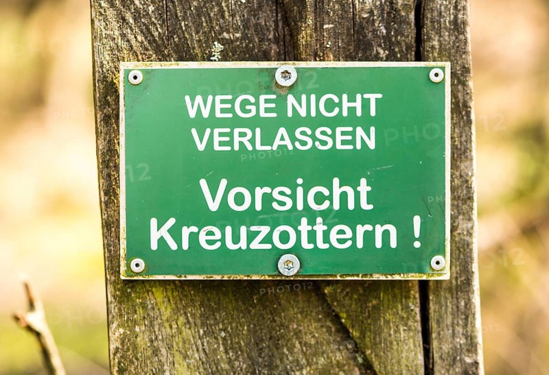 Sign: Do not leave the paths, beware of common european vipers (Vipera berus), warning of poisonous snakes in green and white hangs on a pole, Pietzmoor nature reserve, Lüneburg Heath, Lower Saxony, Germany, Europe