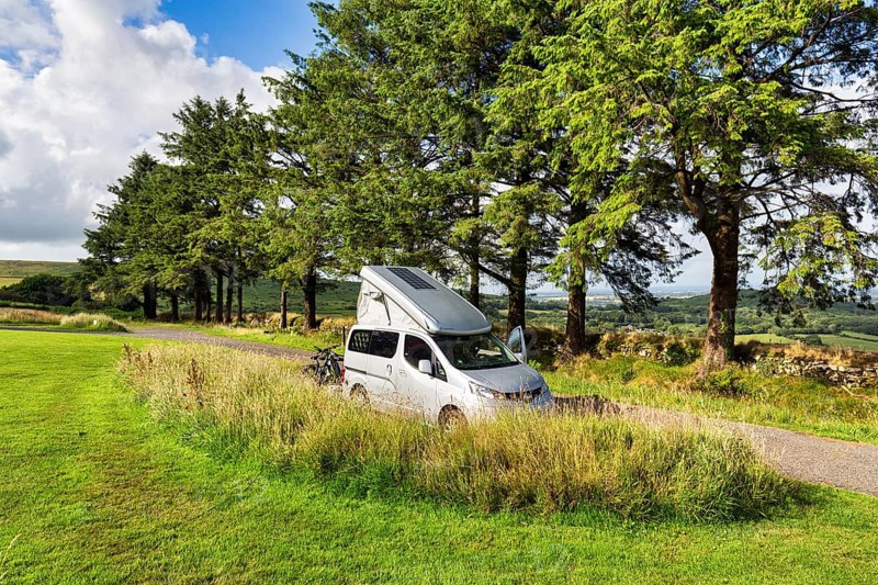 Campervan with pop-up roof, pop-up roof with solar panel, Nissan NV200 minicamper, camping. Bodmin Moor, sunny weather, Cornwall, England, United Kingdom, Europe