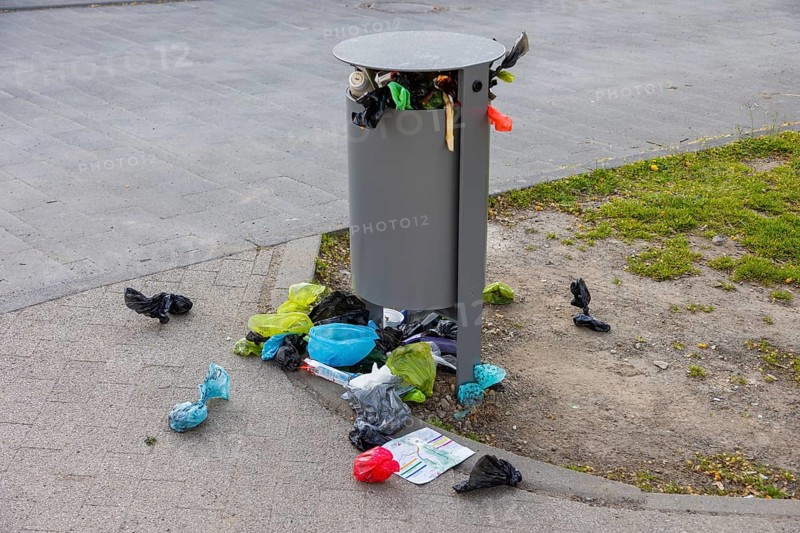 Public waste bin at leipzig city harbour, completely overcrowded, pet owners throw their dog waste bags carelessly beside it
