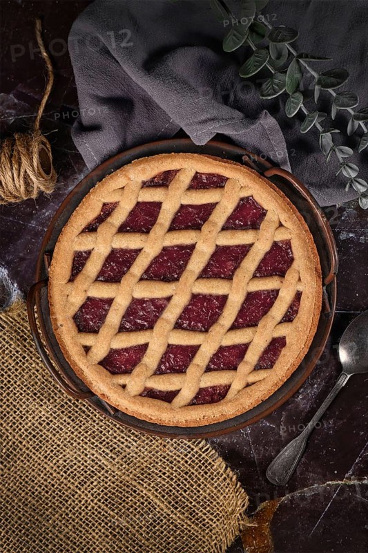 Top view of homemade pie called 'Linzer Torte', a traditional Austrian shortcake pastry topped with fruit preserves and sliced nuts with lattice design