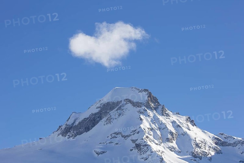 White cloud over snow covered mountain top, pinnacle Ciarforon in winter in the Gran Paradiso Massif of the Graian Alps, Aosta Valley, Italy, Europe