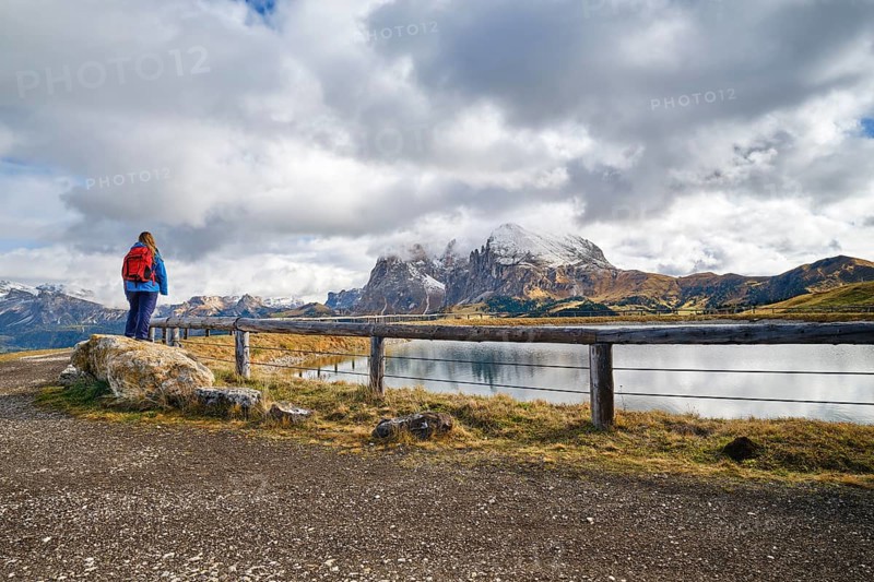 Hiker standing on stone, Sassopiatto, Sassolungo, Dolomites, Alpe di Siusi, lake, snow, clouds, Castelrotto, South Tyrol