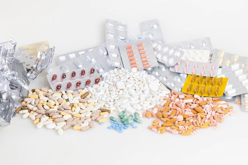Empty and full blister packs with tablets of different colours and shapes, white background