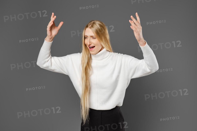 Dissatisfied young woman swears and gesticulates emotionally with her hands