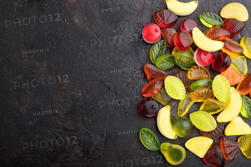 Various fruit jelly candies on black concrete background. top view, flat lay, copy space