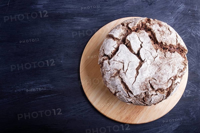 Yeast free homemade bread with whole rye and wheat grains on black wooden background. Top view, copy space