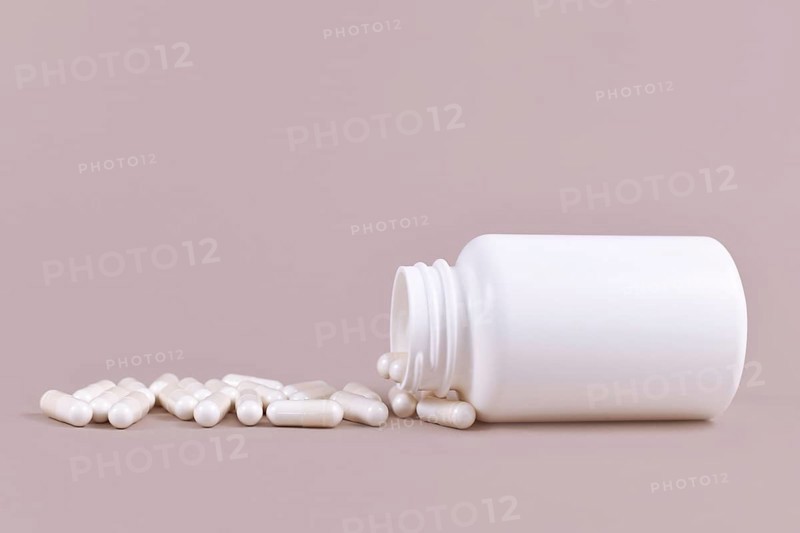 Medical capsule pills spilling from blank container