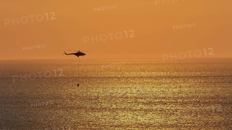 Helicopter, helicopter, fire-fighting helicopter, close over the sea, sunset, sun reflections on the sea, fire, Falassarna, West Crete, Crete, Greece, Europe