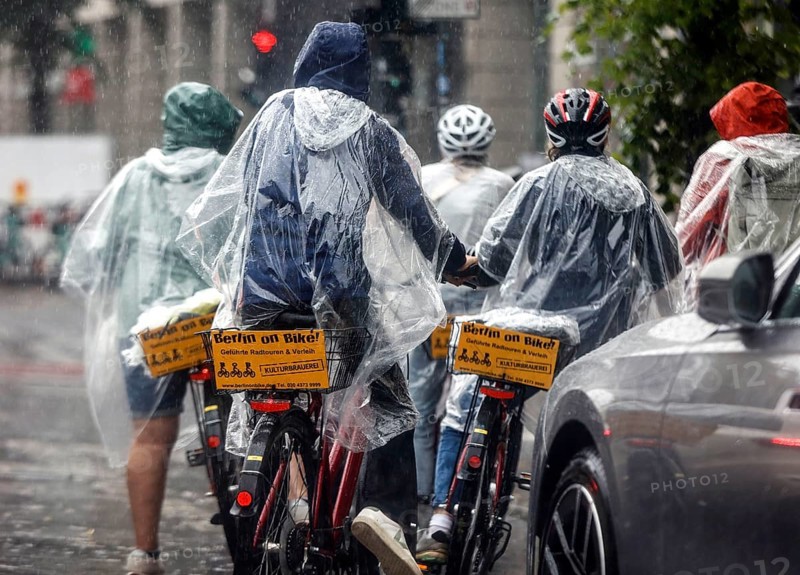 Tourists on a Berlin On Bike bike tour with rain capes in heavy rainfall, Berlin, 23 06 2023