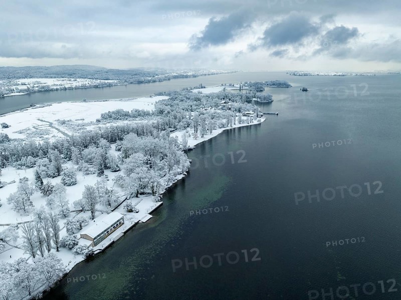 Aerial view of the snow-covered Mettnau peninsula with the Mettnaupark, on the horizon the island of Reichenau, Radolfzell on Lake Constance, district of Constance, Baden-Württemberg, Germany, Europe