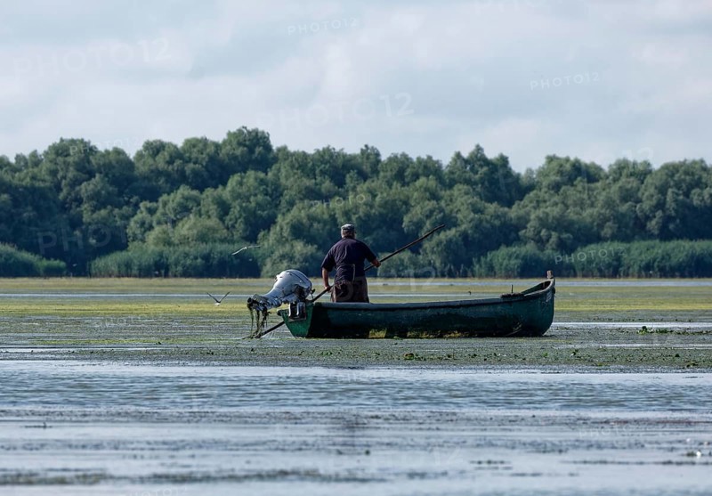 Fishermen in a boat on the water of Lacul Isaccel, a lake in the Danube Delta. UNESCO Danube Delta Biosphere Reserve. Munghiol, Tulcea, Romania, Southeast Europe, Europe