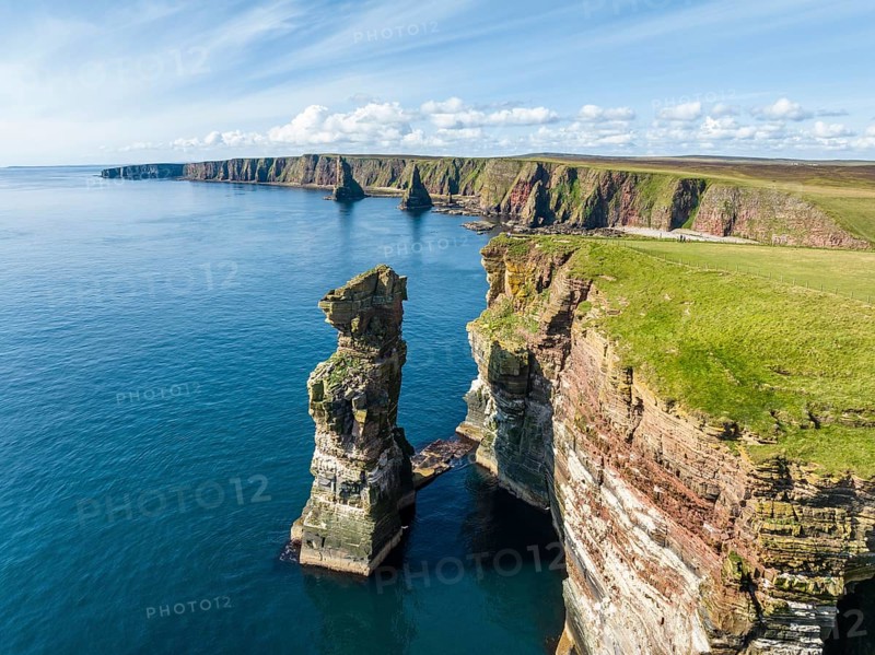 Aerial view of the rugged coastal landscape at Duncansby Head with rock tower, behind it the Duncansby Stacks, County Caithness, Scotland, Great Britain