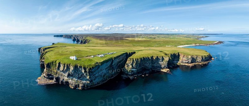 Aerial panorama of the rugged coastal landscape at Duncansby Head with the lighthouse, behind it the rock formation Duncansby Stacks, to the right on the horizon the village of John o' Groats, Scotland's north-eastern point, County Caithness, Scotland, United Kingdom, Europe