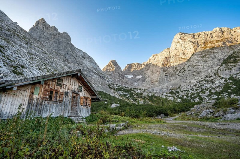 Cosy mountain hut Blaueishütte, behind rocky mountain peaks SchÃ¤rtenspitze, Blaueisspitze and Hochkalter at sunrise, mountain tour on the Hochkalter, Hochkalter crossing, Berchtesgaden Alps, Bavaria, Germany, Europe