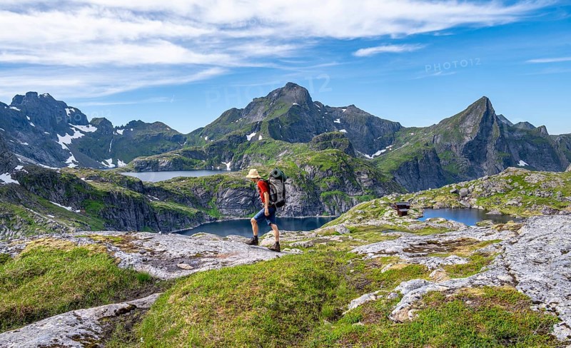 Mountaineer, mountain landscape with rocky pointed peaks and lakes, with mountain Hermannsdalstinden and lakes Tennesvatnet and Krokvatnet, Moskenesoya, Lofoten, Nordland, Norway, Europe