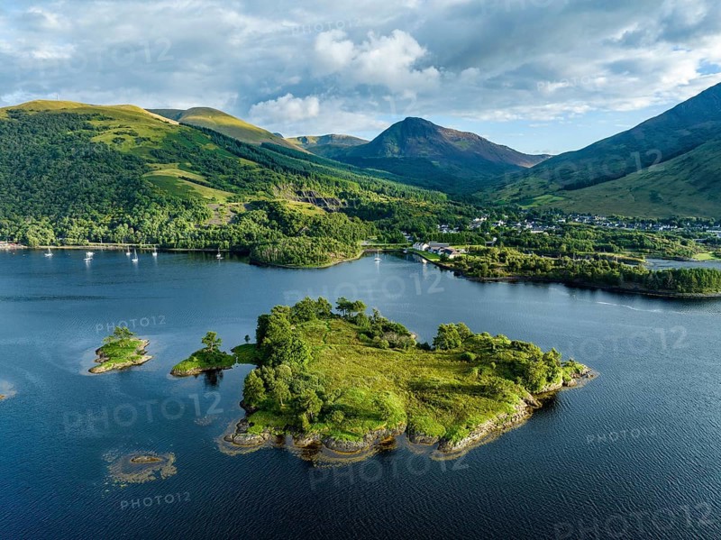 Aerial view of the island of Eilean Munde, behind it the village of Ballachulish with the harbour and the former slate quarry at the western part of the freshwater loch Loch Leven, Highlands, Scotland, Great Britain