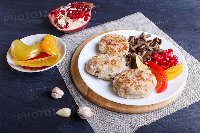 Meatballs with rice mushrooms, sweet peppers and pomegranate seeds on black wooden background. close up