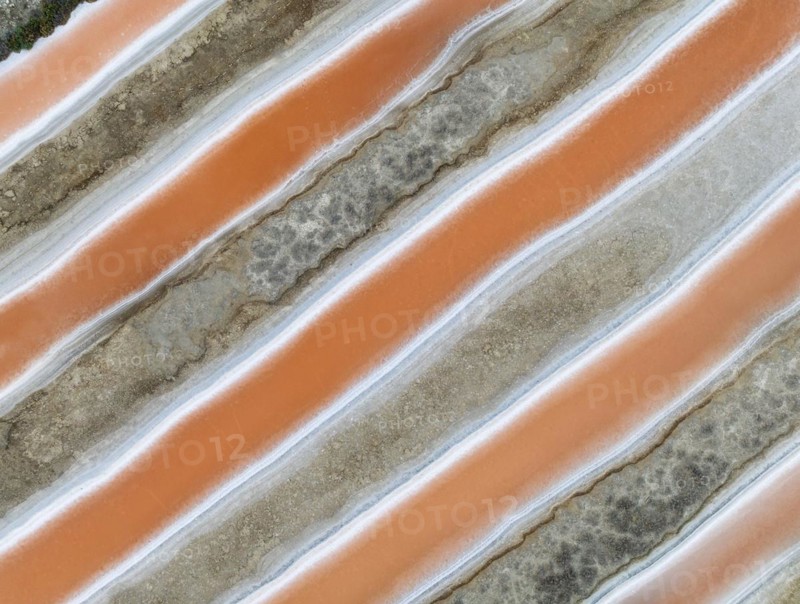 Saline ponds at the salt works near Chiclana de la Frontera. The orange-red colour depends on the level of salinity and is directly caused by the algae Dunaliella salina and brine shrimp. Aerial view. Drone shot. Cadiz province, Andalusia, Spain, Europe