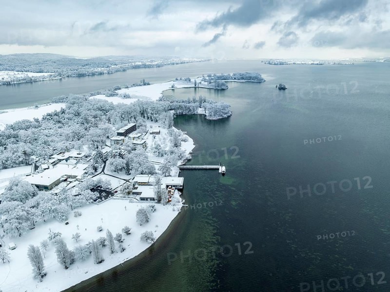 Aerial view of the snow-covered Mettnau peninsula with the Mettnau park, spa centre and beach café, Reichenau island on the horizon, Radolfzell on Lake Constance, Constance district, Baden-Württemberg, Germany, Europe