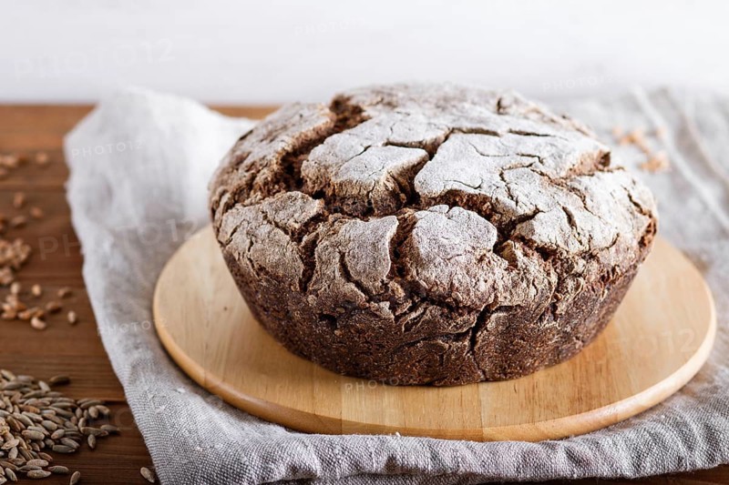 Yeast free homemade bread with whole rye and wheat grains on rustic wooden background. close up