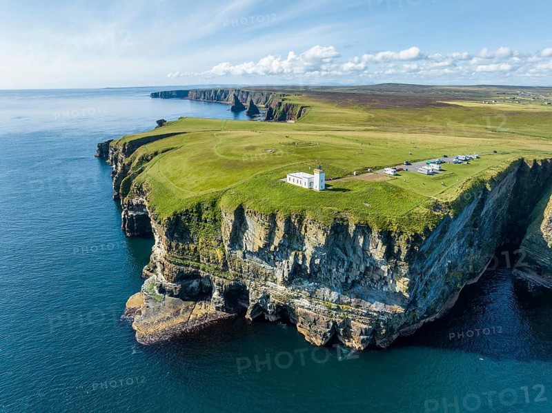Aerial view of the rugged coastal landscape at Duncansby Head with the lighthouse and the Duncansby Stacks rock formation behind, Scotland's north-eastern point, County Caithness, Scotland, United Kingdom, Europe