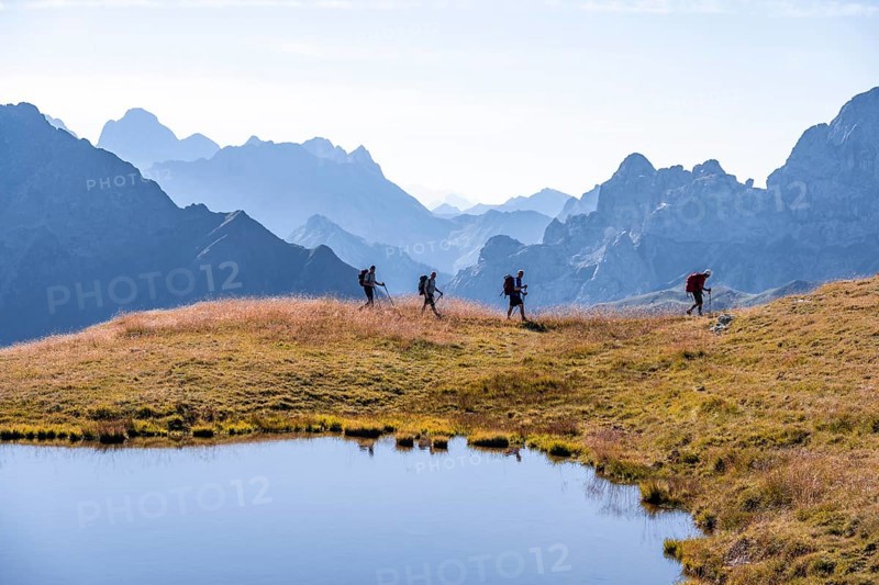 Four hikers on the Carnic High Trail, small mountain lake, Carnic Main Ridge, Carnic Alps, Carinthia, Austria, Europe