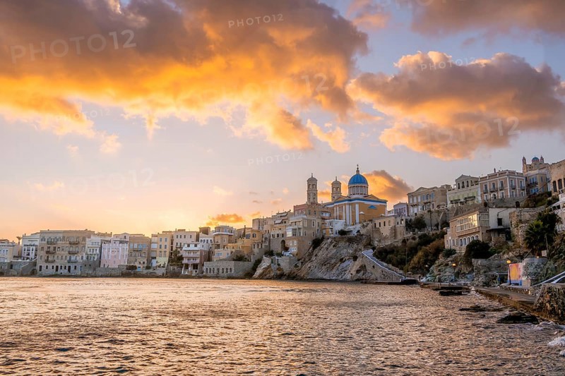 View of the village with the Greek Orthodox church of Agios Nikolaos, Asteria Beach, at sunset with atmospheric clouds, Ermoupoli, Syros, Cyclades, Greece, Europe