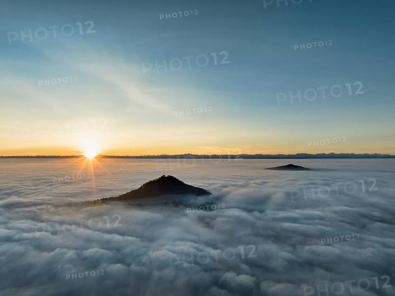 Aerial view of the wintry and fog-covered Hegaulandschaft at sunrise, the volcanic cones Hohenhewen and to the right the Hohenstoffeln rise out of the sea of fog, on the horizon the Alpine chain, district of Constance, Baden-Württemberg, Germany, Europe