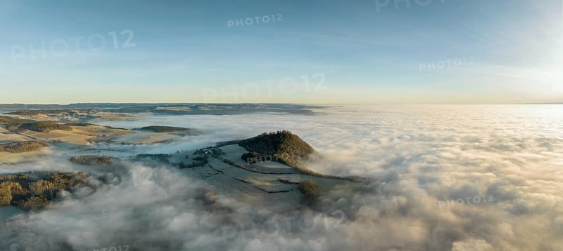 Aerial panorama of the wintry and fog-covered Hegaulandschaft shortly after sunrise, the volcanic cone Hohenhewen rises out of the sea of fog, district of Constance, Baden-Württemberg, Germany, Europe