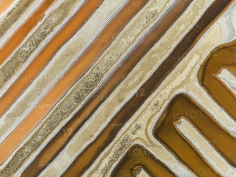 Saline ponds at the salt works near Chiclana de la Frontera. The orange-red colour depends on the level of salinity and is directly caused by the algae Dunaliella salina and brine shrimp. Aerial view. Drone shot. Cadiz province, Andalusia, Spain, Europe