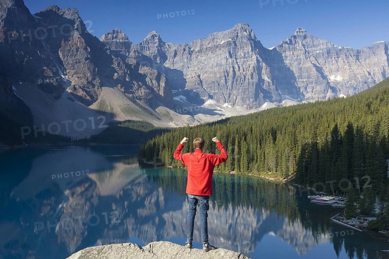 Tourist with open arms on look-out point looking over Moraine Lake in the Valley of the Ten Peaks, Banff National Park, Alberta, Canada | MR:yes Arndt Kobbe