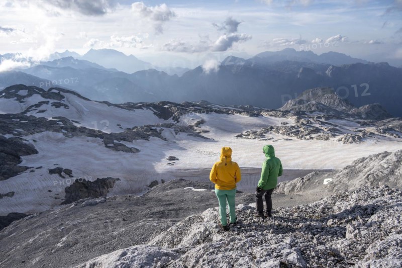 High alpine landscape, snowfields and rock, Two hikers look down into the valley from the Hochkönig, Salzburger Land, Austria, Europe