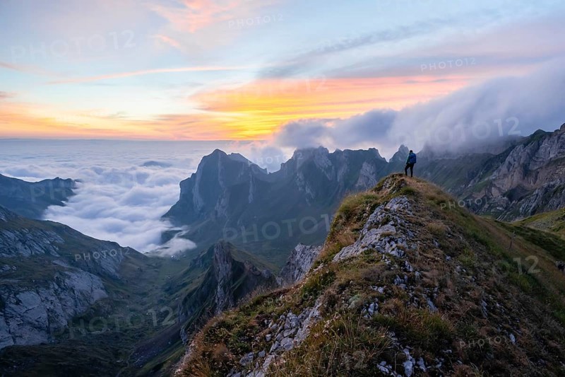 Hiker on the mountain, view over SÃ¤ntis mountains into the valley of Meglisalp at sunrise, high fog in the valley, SÃ¤ntis, Appenzell Ausserrhoden, Appenzell Alps, Switzerland, Europe