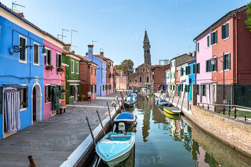 Colourful houses on the canal, canal with boats and colourful house facades, behind the church tower of the Chiesa Parrocchiale di San Martino Vescovo, island of Burano, Venice, Veneto, Italy, Europe