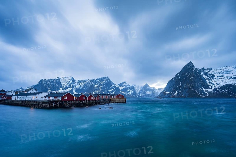 Rorbuer cabins of Hamnoy by the fjord, snowy mountains in the back, Hamnoy, Reine, Moskenesoya, Lofoten, Norway, Europe