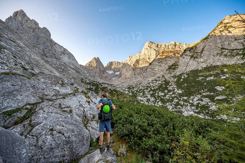 Mountaineer on a mountain path, rocky mountain peaks SchÃ¤rtenspitze, Blaueisspitze and Hochkalter at sunrise, mountain tour on the Hochkalter, Hochkalter crossing, Berchtesgaden Alps, Bavaria, Germany, Europe